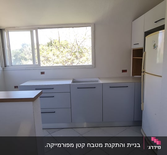 מטבח עם ארונות לבנים ומקרר לבן